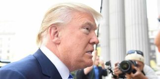 Man in suit with photographers in background.