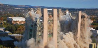 A building being demolished with dust and debris in the air