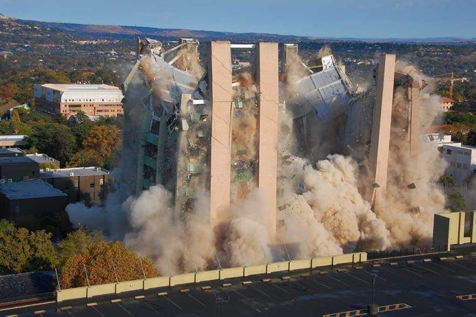 shutterstock_101827756.jpg A building being demolished with dust and debris in the air