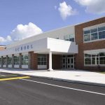 Educators ARM Students – ICE School Battlegrounds! Modern school building with large windows and a clear sky