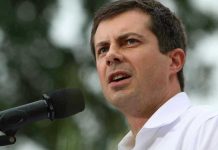 Man speaking into microphone outdoors.