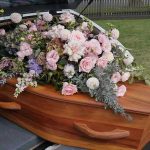 Coffin with flowers in the back of a hearse.