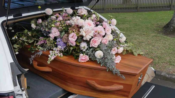 1929477455 Coffin with flowers in the back of a hearse.
