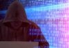 Person in hoodie using laptop surrounded by digital code