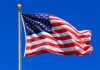 American Dream DEAD – Gen Z Plots Escape Waving American flag against a clear blue sky