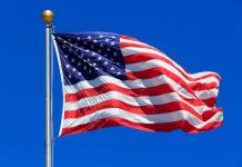 American Dream DEAD – Gen Z Plots Escape Waving American flag against a clear blue sky
