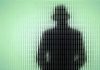 Mystery Deepens: Anti-AI Leader DISAPPEARS Silhouette behind frosted, textured glass in green light.