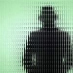 Mystery Deepens: Anti-AI Leader DISAPPEARS Silhouette behind frosted, textured glass in green light.