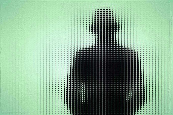 Silhouette behind frosted, textured glass in green light.