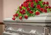 Silver casket with red rose arrangement on top.