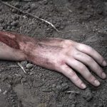 Injured arm partially buried in dirt.