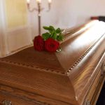 Wooden casket with red roses on top.