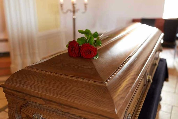 664198003 Wooden casket with red roses on top.
