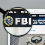FBI IN TURMOIL: Patel’s Alleged Misuse Of Resources FBI website shown through magnifying glass.