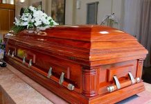 Wooden casket with white flowers in a funeral home.