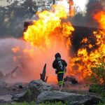Unseen Fire Crisis Hits North Georgia Firefighter battling a large fire with water spray