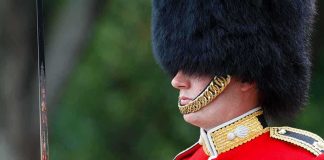 British soldier in ceremonial uniform with a black fur hat standing guard
