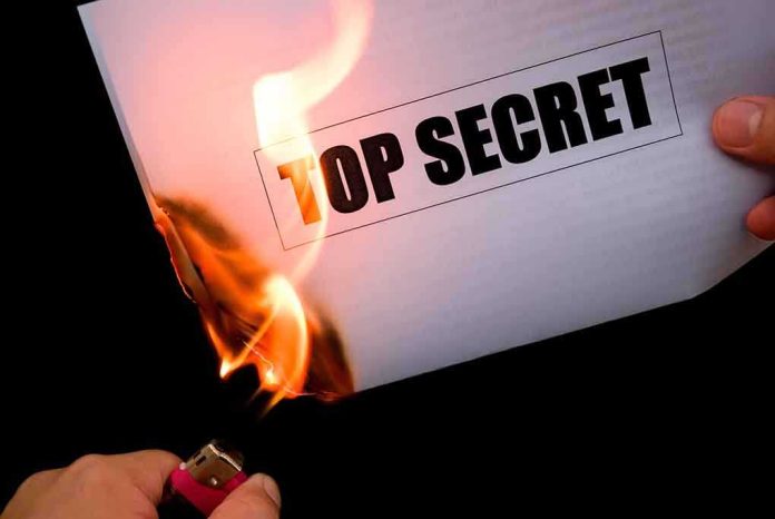 shutterstock_144202225.jpg A hand holding a lighter igniting a paper labeled TOP SECRET as it catches fire