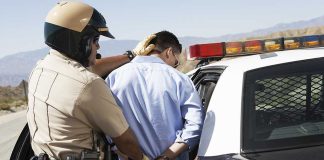 Police officer arresting a suspect near a patrol car