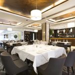 Influencer’s Dine-and-Dash Lands Her in JAIL Interior of a modern restaurant with elegantly set tables and a bar area