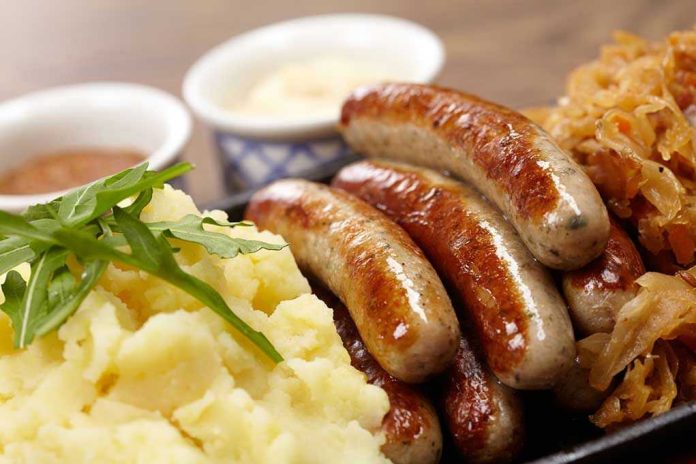 101880892 Sausages, mashed potatoes, sauerkraut, and sauces on plate.