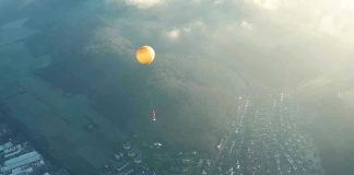 Orange hot air balloon above a town in fog.