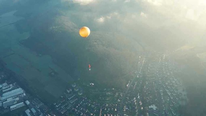 1351838594 Orange hot air balloon above a town in fog.