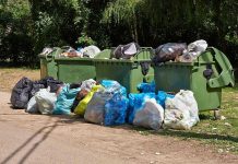 Scientists PROGRAM Plastic to Self-Destruct Overflowing garbage bins with bags on the ground.
