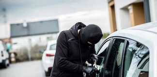 Person in black breaking into a car.