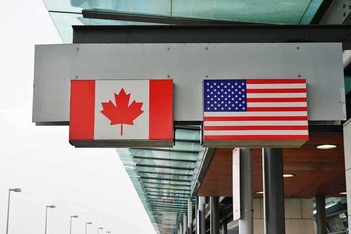 shutterstock_1044483421 (2).jpg Canadian and American flags displayed at a border crossing