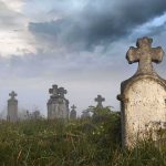 Foggy graveyard with tombstones and crosses under a cloudy sky