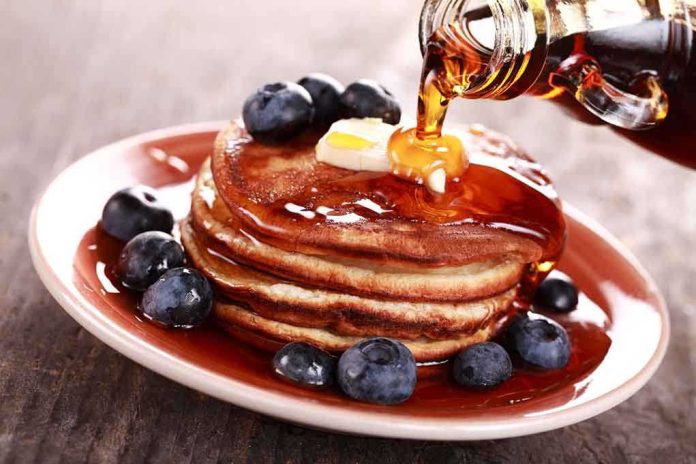 Stack of pancakes topped with butter and blueberries, drizzled with maple syrup