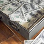 $85K Theft Triggers QUADRUPLE Family Massacre A briefcase filled with hundred dollar bills on a wooden surface