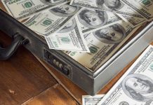 A briefcase filled with hundred dollar bills on a wooden surface