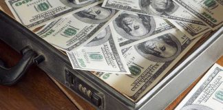 A briefcase filled with hundred dollar bills on a wooden surface