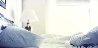 A cozy unmade bed with soft pillows and bedding in a well-lit room