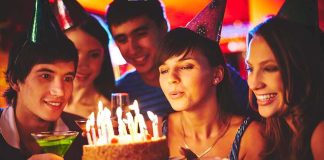 Group of friends celebrating a birthday with a cake and drinks