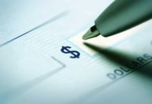 Turning Point USA PLEDGES Trump Account Match Close-up of a pen poised over a check with a dollar sign