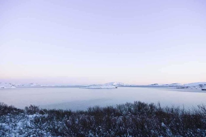 shutterstock_71379826.jpg A serene winter landscape featuring a calm lake surrounded by snow-covered mountains under a twilight sky