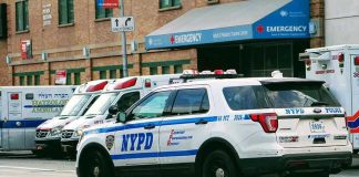 Police car and ambulances outside emergency room entrance.