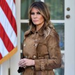 Melania Documentary DEFIES Rural America Woman in brown coat beside American flag.