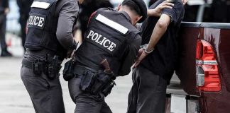 Police officers arresting a handcuffed person.