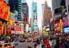 Times Square crowded with people and bright electronic advertisements.