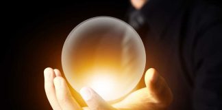 A hand holding a glowing crystal ball against a dark background