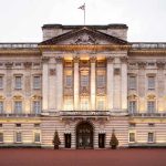 Front view of Buckingham Palace with illuminated facade and British flag
