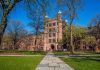 Historic university building surrounded by green grass and trees under a blue sky