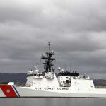 A U.S. Coast Guard ship docked under cloudy skies