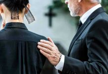 Man comforting woman at funeral service.