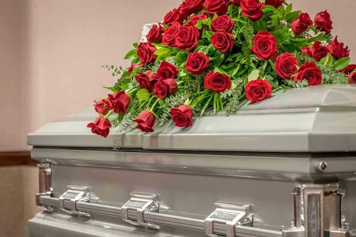 1734828347 Silver casket with red rose arrangement on top.