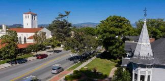 Street with church, parked cars, and trees.